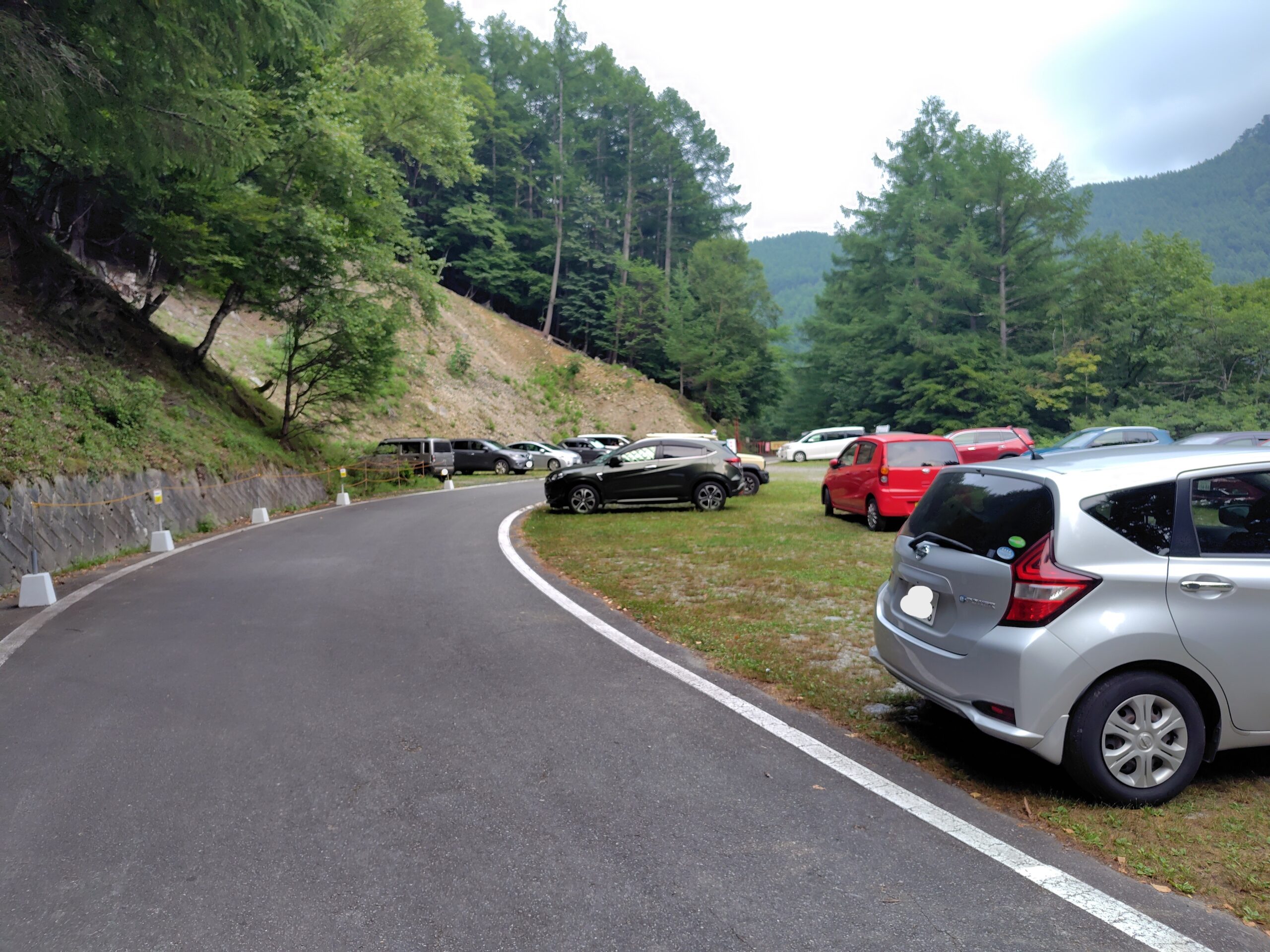 鳥倉登山口駐車場の第1駐車場。舗装された林道脇に数台の車が駐まっている