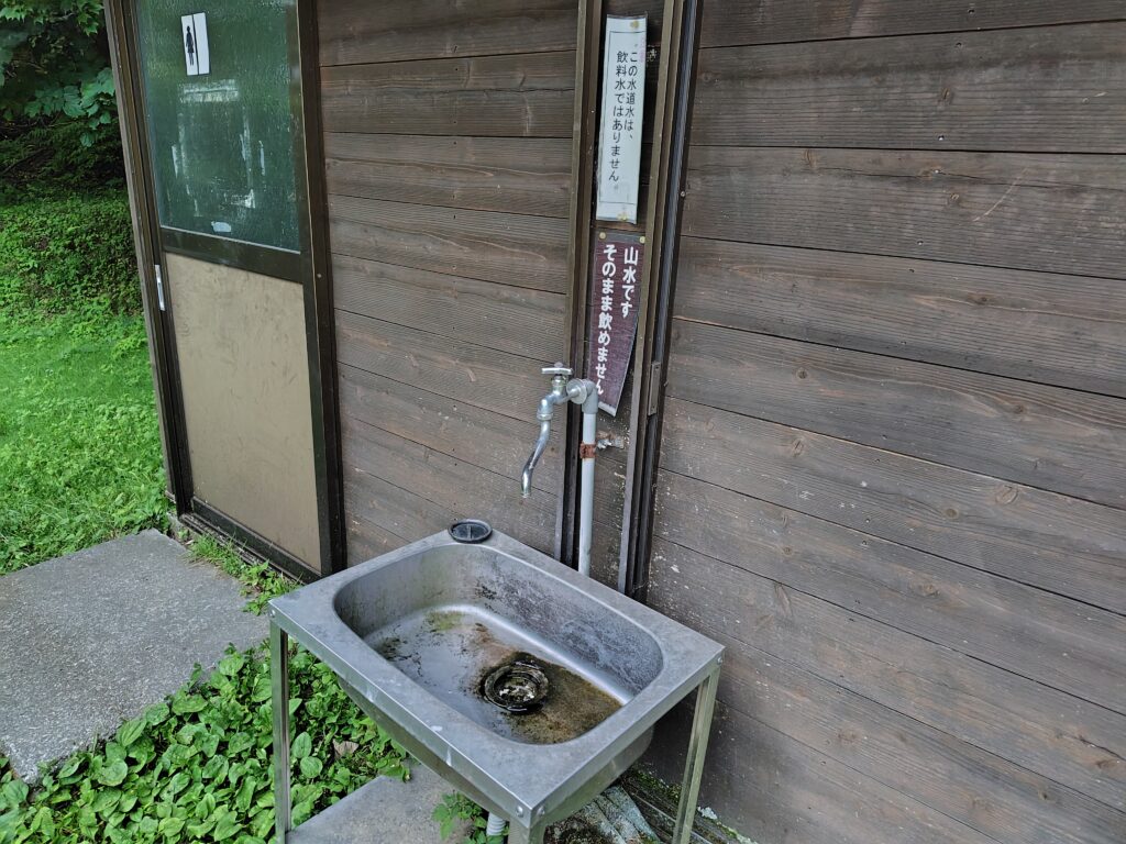 トイレ横の手洗い場。沢の水を利用しており飲用には適さない旨の貼り紙がある
