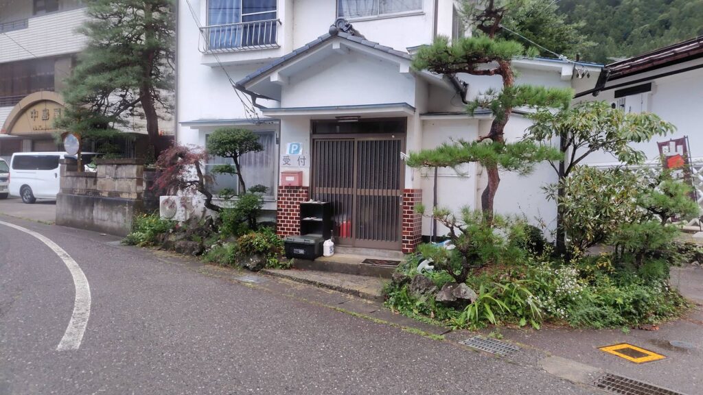 駐車場の受付をしている民家の玄関。「P 受付」の看板が出ている