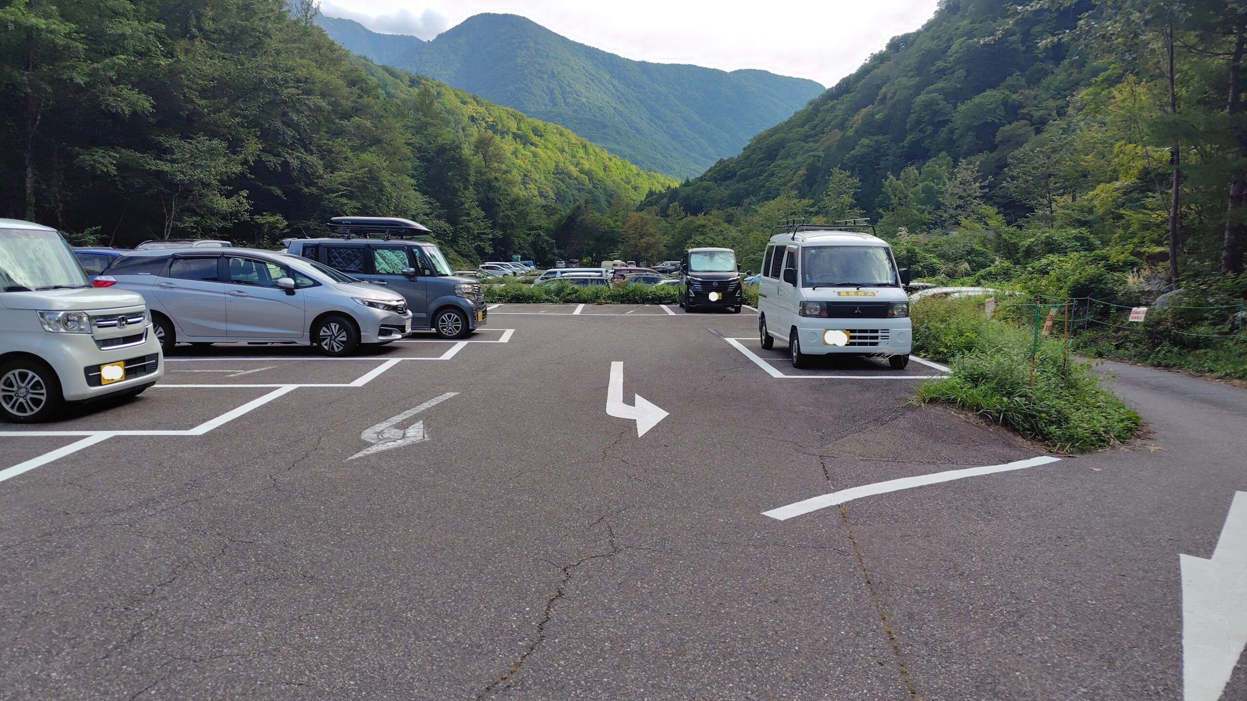 新穂高の登山者用無料駐車場。奥飛騨の山に囲まれた区画に乗用車が並んでいる