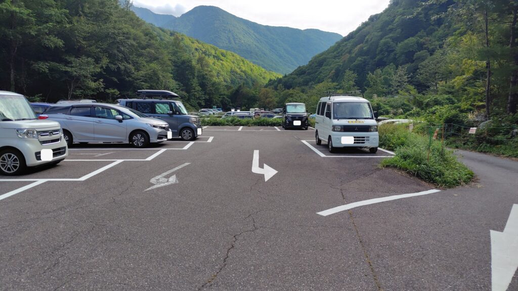 新穂高の登山者用無料駐車場。奥飛騨の山に囲まれた区画に乗用車が並んでいる